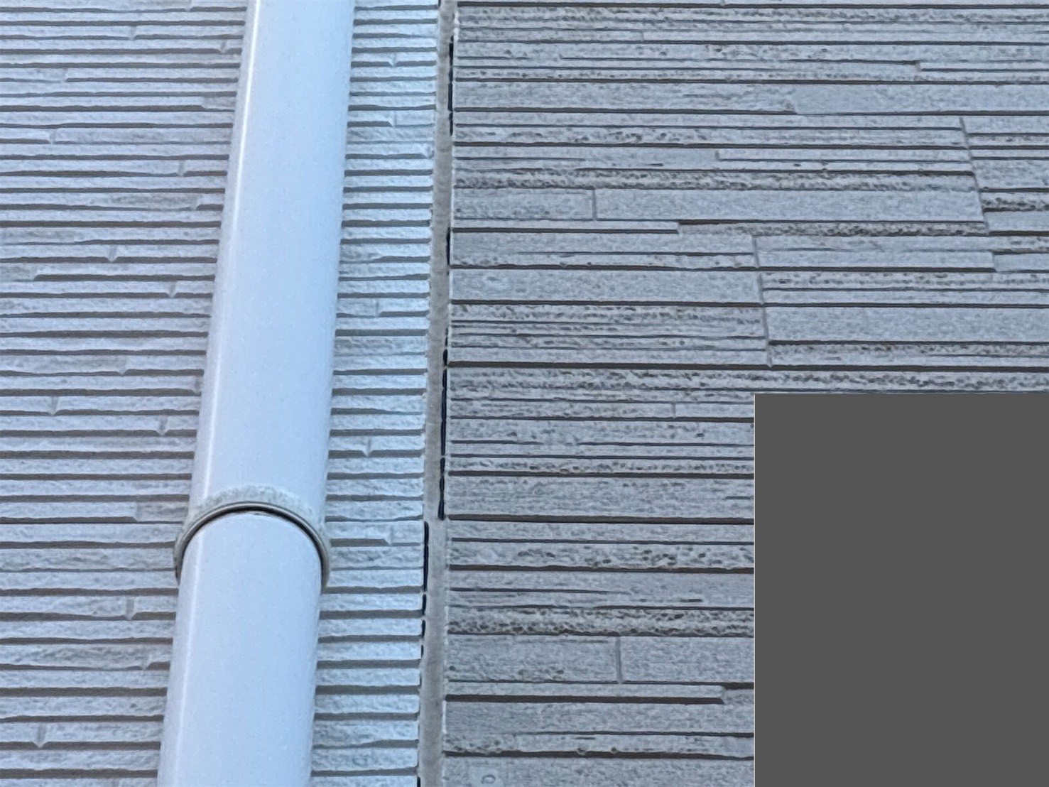 白い樋とシーリングが切れたサイディング