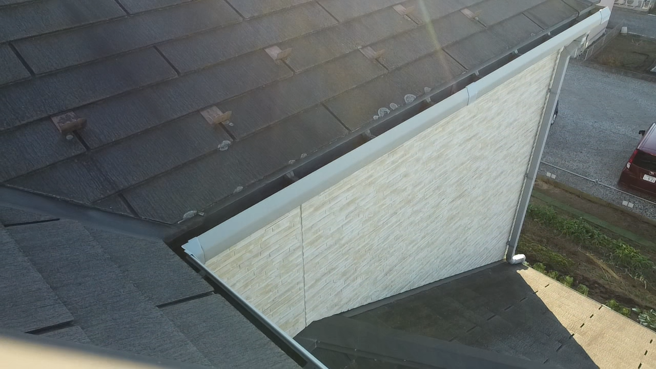 軒先が劣化したスレート屋根と白い外壁