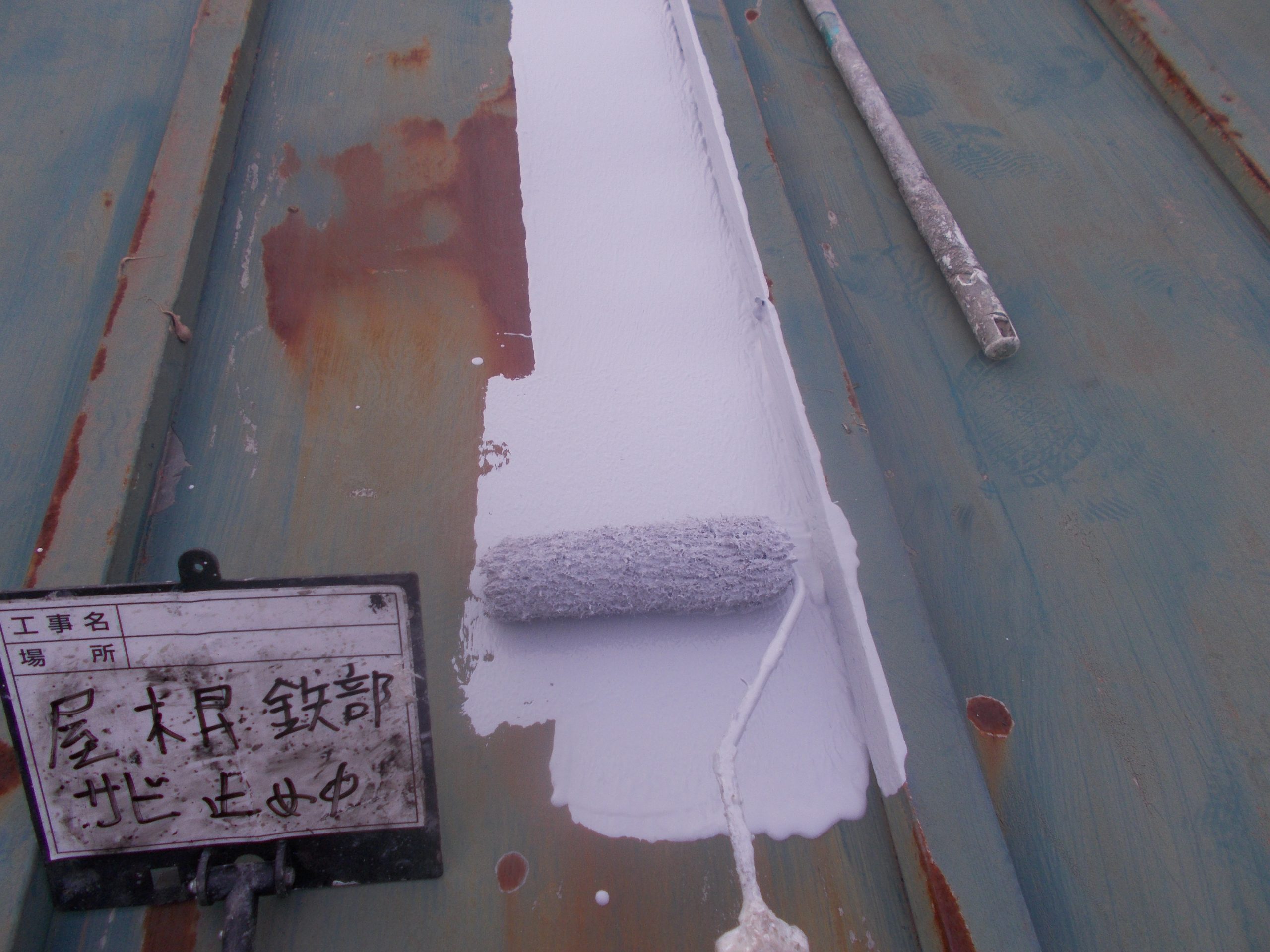 さびた金属屋根に錆止め塗装を施工中