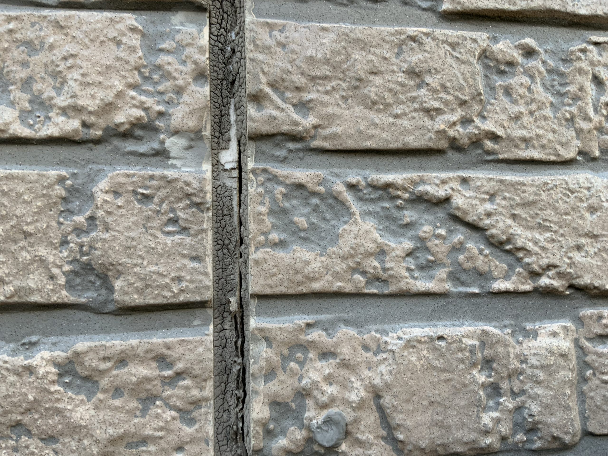 シーリングが剥離した石目調の外壁