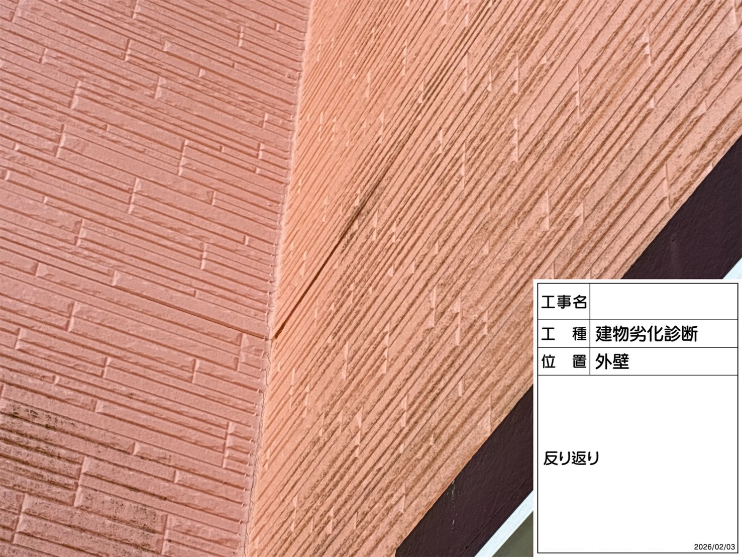 汚れたピンクの外壁が反り返っている