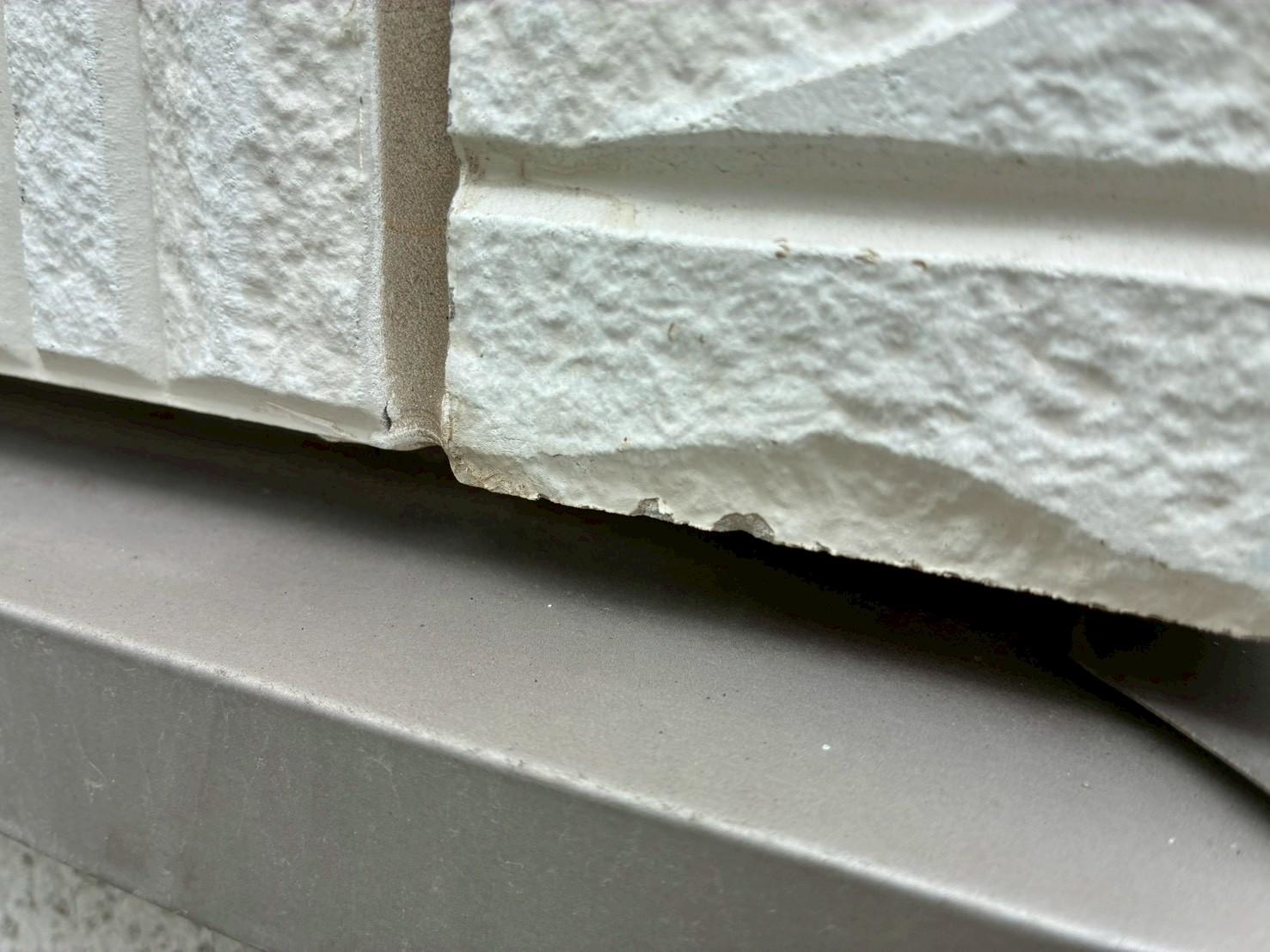 白いサイディングの下端が欠けている