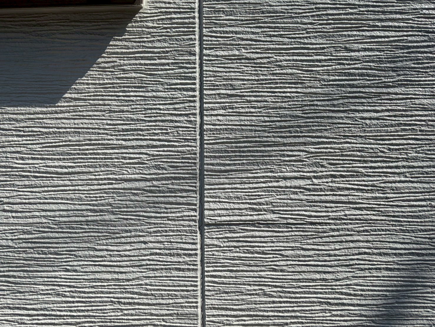 白いサイディングの一部に反りが発生