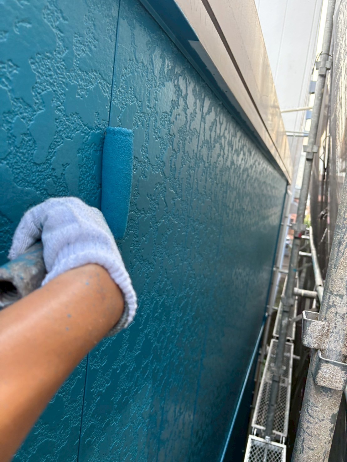 青い塗料で上塗り施工中