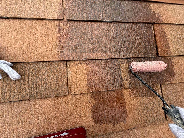 ローラーでスレート屋根に下塗り材を塗布する作業の様子
